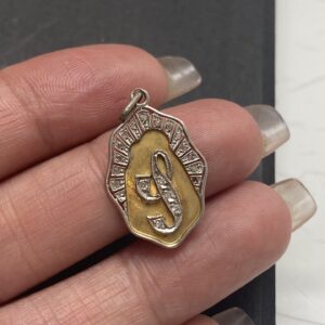 Colgante antiguo de oro 8K y diamantes con un emblema central en relieve, rodeado por un marco con detalles grabados. La pieza muestra un refinado trabajo artesanal típico del estilo Art Deco.