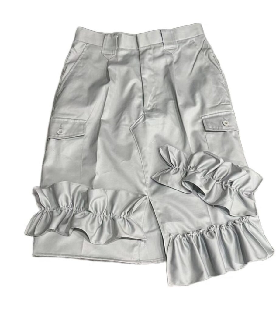 Falda de estilo cargo en tela satinada color gris, con bolsillos y detalles de volantes decorativos en el bajo.