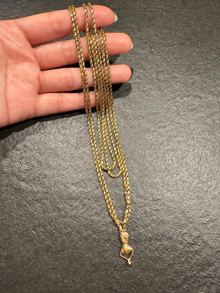 Un collar de oro con diseño único y una presencia inigualable: eslabones geométricos y un colgante ornamentado con detalles artesanales.